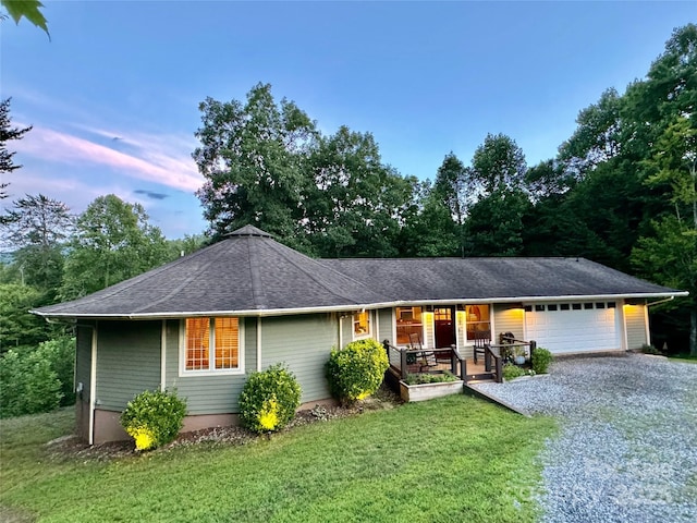 ranch-style home featuring a lawn, a porch, and a garage