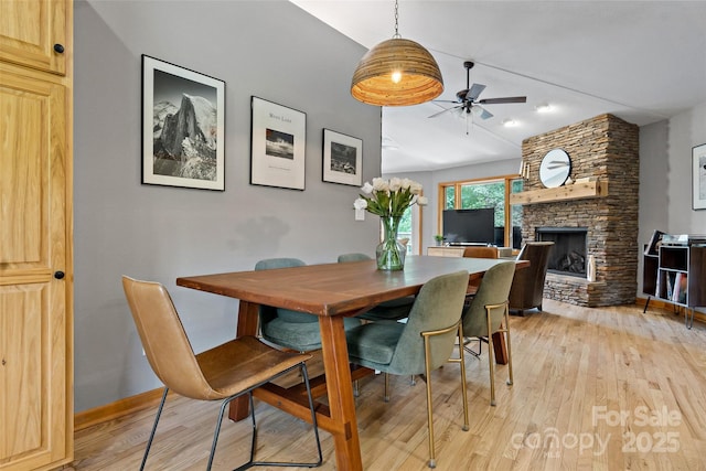 dining area featuring ceiling fan, a fireplace, and light hardwood / wood-style flooring