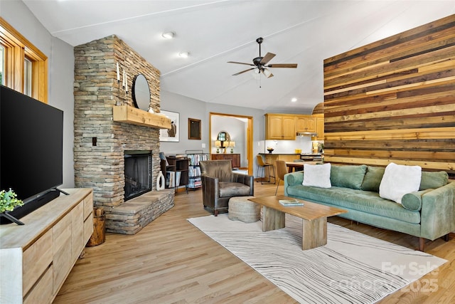 living room with light hardwood / wood-style floors, lofted ceiling, ceiling fan, and a fireplace