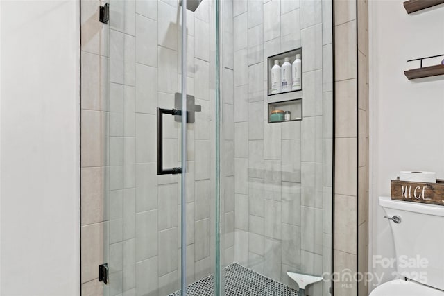 bathroom featuring toilet and a shower with door