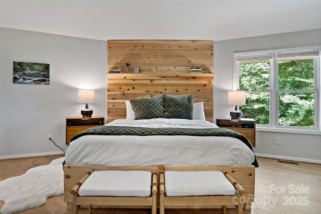 bedroom with light hardwood / wood-style flooring and wood walls