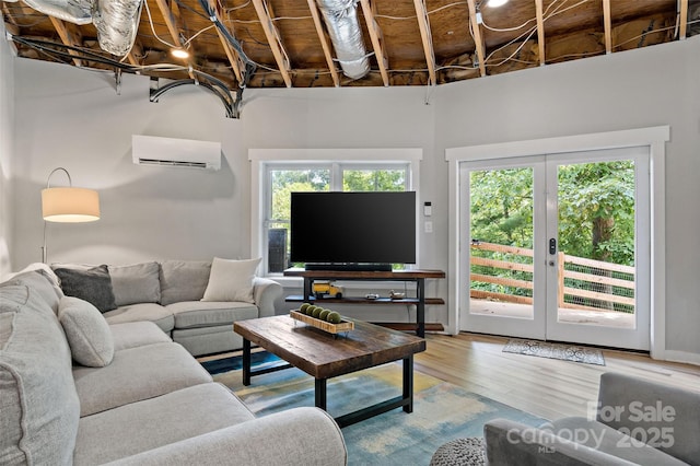 living room with wood-type flooring, french doors, and a wall unit AC