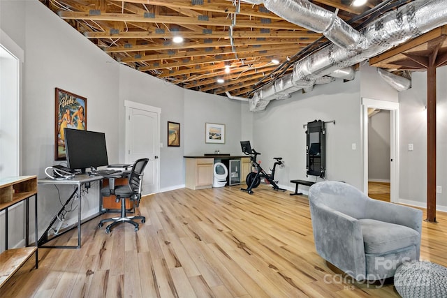 home office with light hardwood / wood-style floors and a high ceiling