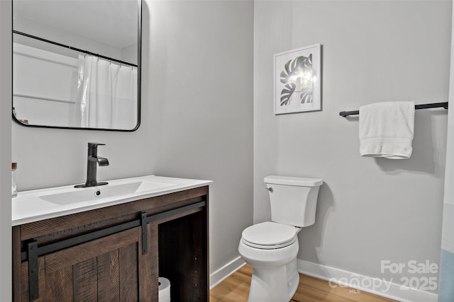 bathroom with toilet, vanity, walk in shower, and hardwood / wood-style floors