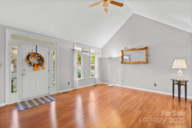 entryway with ceiling fan, high vaulted ceiling, and light hardwood / wood-style flooring