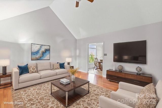 living room with ceiling fan, high vaulted ceiling, and light wood-type flooring