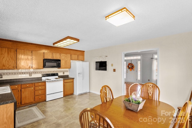 kitchen featuring sink, a textured ceiling, white appliances, and decorative backsplash