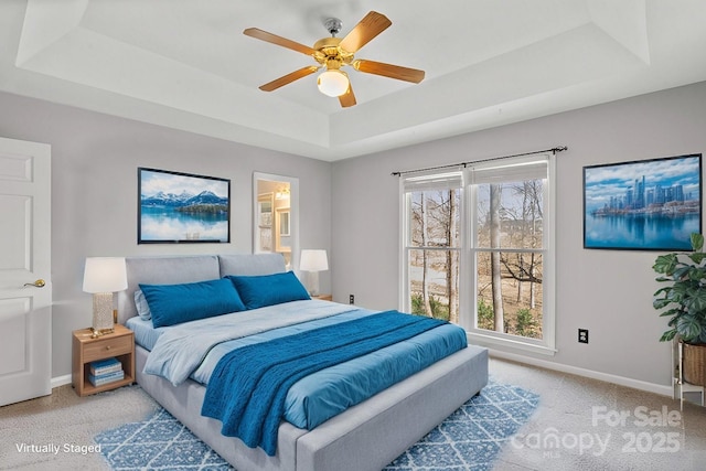 bedroom featuring ceiling fan, light colored carpet, and a tray ceiling