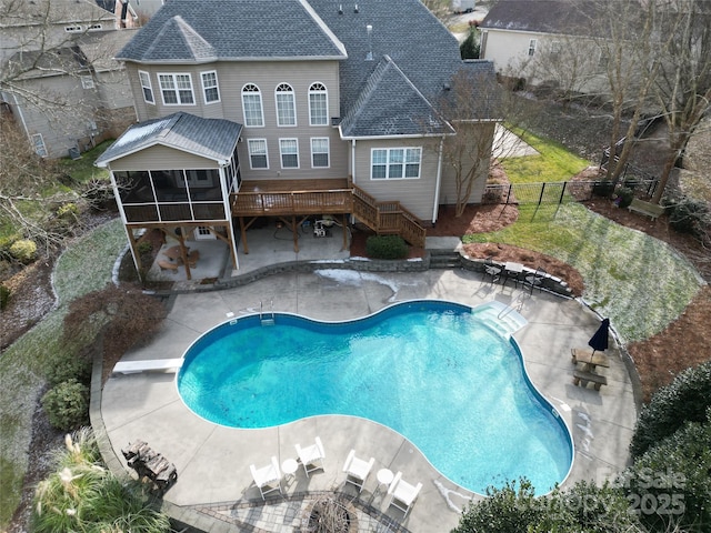 view of pool with a wooden deck, a diving board, a patio area, and a sunroom