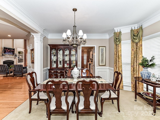 dining area with a notable chandelier, ornamental molding, light hardwood / wood-style floors, and decorative columns