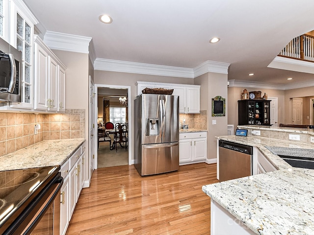 kitchen with crown molding, stainless steel appliances, decorative backsplash, and white cabinets