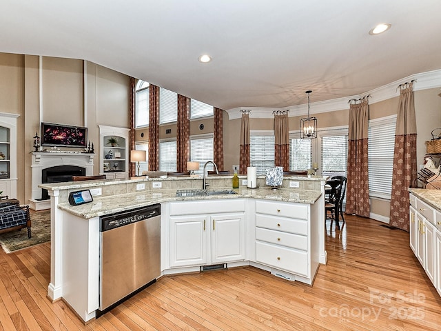 kitchen with sink, light stone counters, decorative light fixtures, dishwasher, and white cabinets