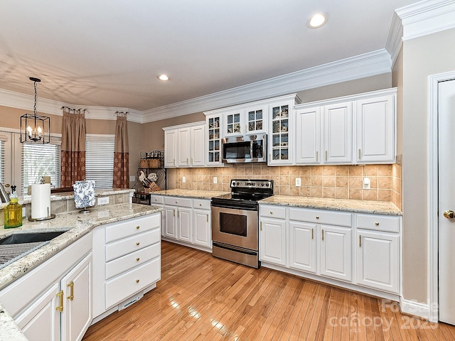 kitchen with stainless steel appliances, ornamental molding, hanging light fixtures, and white cabinets