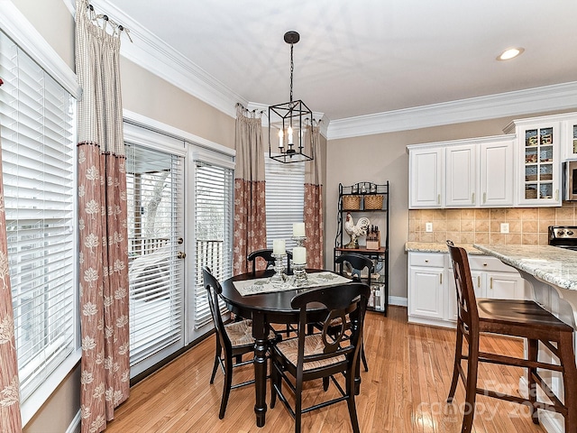 dining room with ornamental molding, an inviting chandelier, and light hardwood / wood-style floors