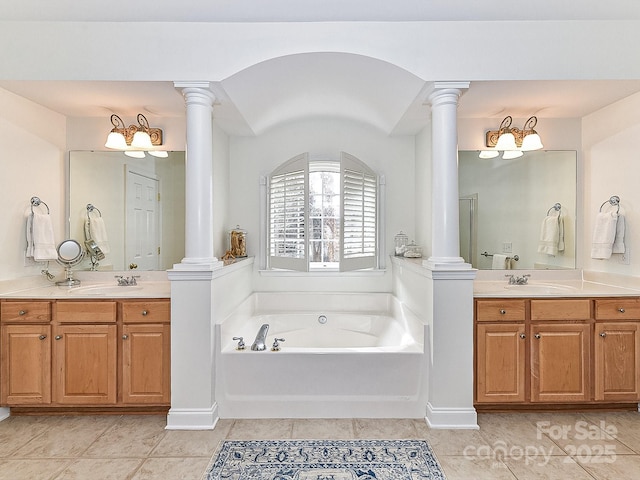 bathroom with tile patterned floors, decorative columns, vanity, and a bathtub