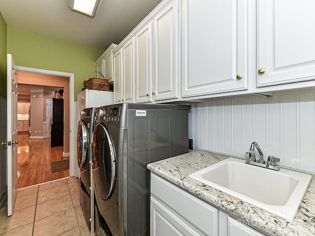 washroom featuring cabinets, light tile patterned flooring, separate washer and dryer, and sink