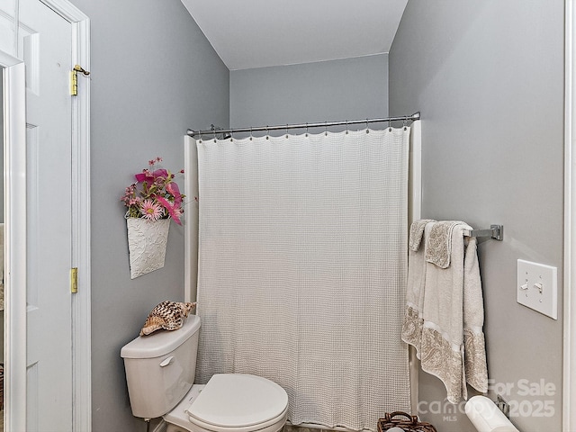 bathroom with curtained shower and toilet