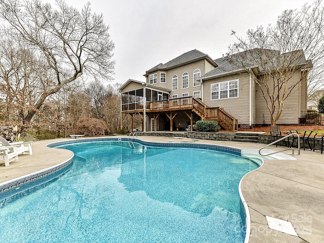 view of swimming pool with a sunroom, a diving board, a deck, and a patio area