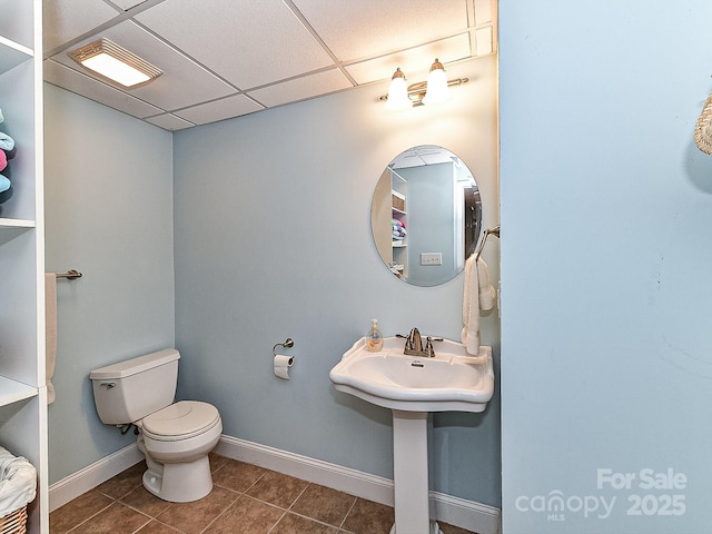 bathroom with a paneled ceiling, toilet, and tile patterned flooring