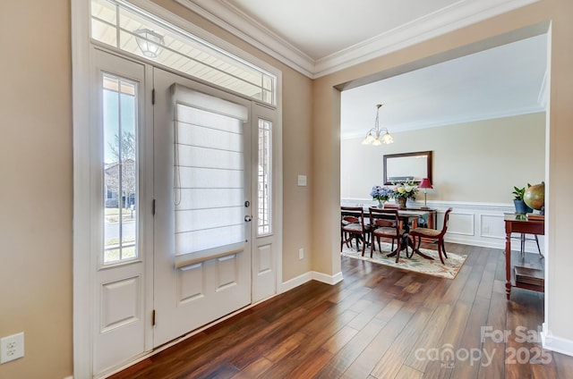 foyer entrance with crown molding, plenty of natural light, dark wood-type flooring, and a notable chandelier