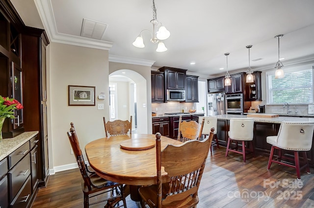 dining room featuring dark hardwood / wood-style floors, ornamental molding, and a notable chandelier