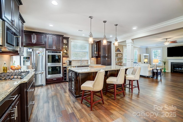 kitchen featuring a kitchen island, decorative light fixtures, a kitchen bar, stainless steel appliances, and crown molding