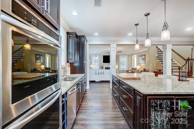 kitchen featuring sink, dark brown cabinets, ornate columns, and pendant lighting