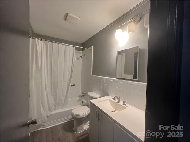 full bathroom featuring tile walls, hardwood / wood-style flooring, vanity, toilet, and shower / bathtub combination with curtain