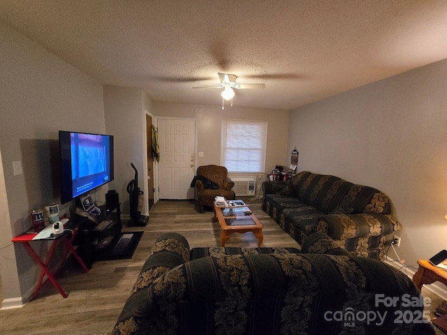 living room featuring wood-type flooring, ceiling fan, and a textured ceiling