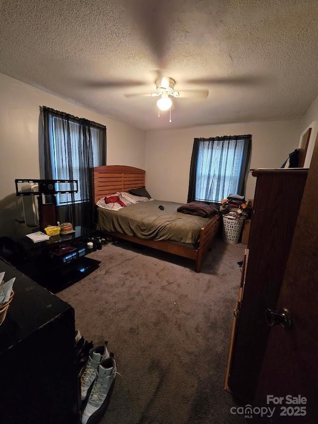 carpeted bedroom featuring ceiling fan and a textured ceiling