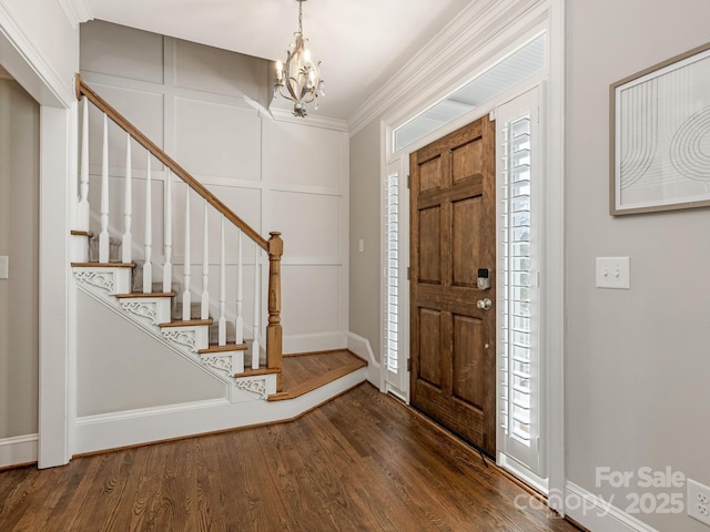 entrance foyer with dark hardwood / wood-style flooring, crown molding, and a chandelier