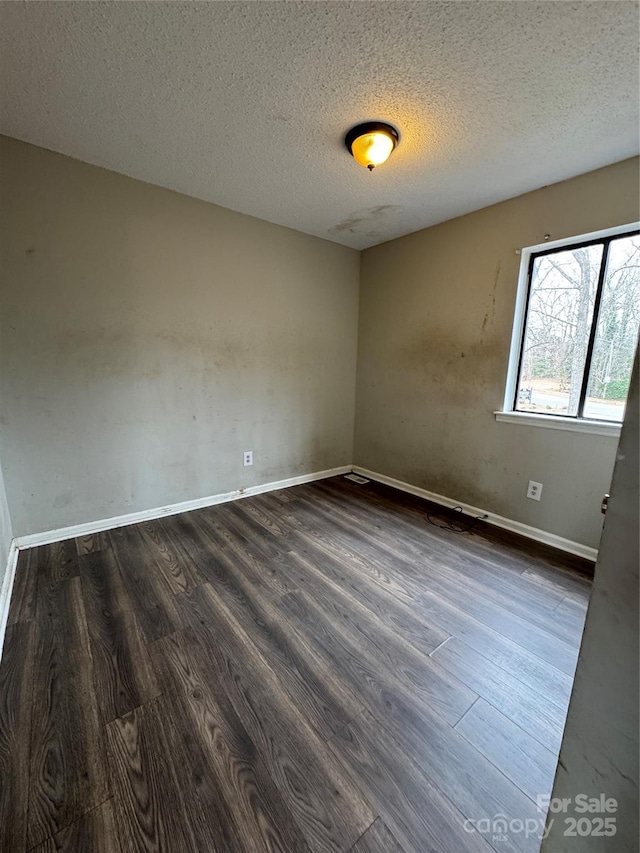 empty room featuring dark wood-type flooring and a textured ceiling