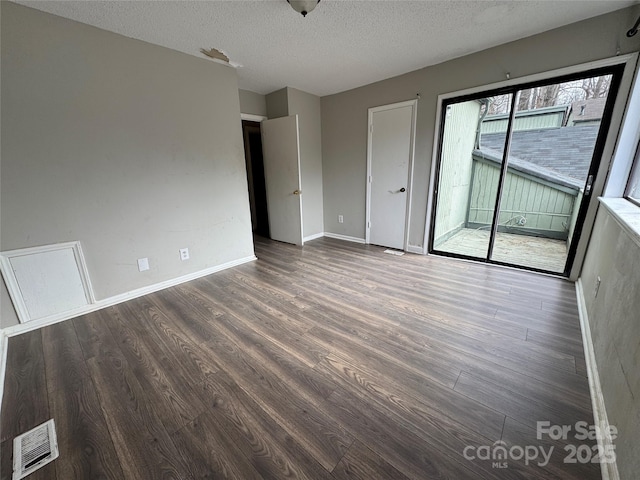 spare room with a textured ceiling and dark hardwood / wood-style floors