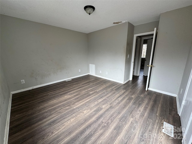 unfurnished room with a textured ceiling and dark hardwood / wood-style floors