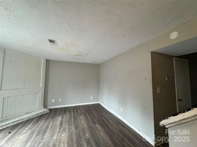 spare room featuring dark wood-type flooring and a textured ceiling