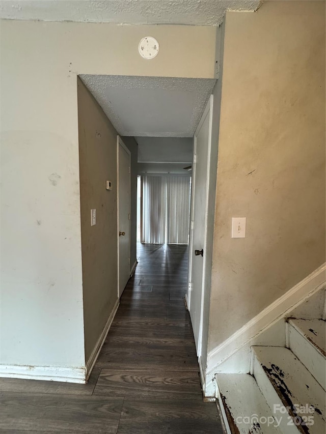 corridor featuring dark wood-type flooring and a textured ceiling