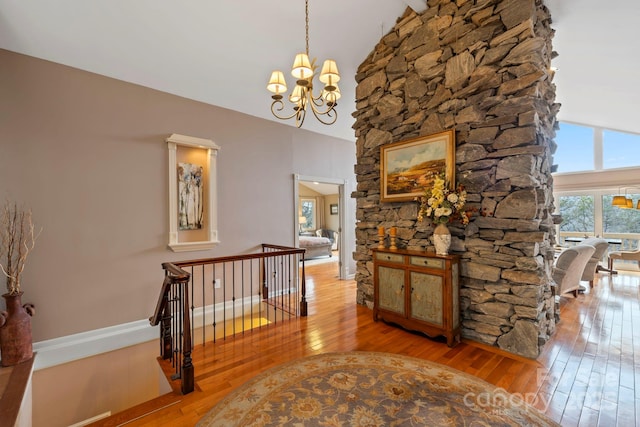 corridor featuring a notable chandelier, hardwood / wood-style flooring, and vaulted ceiling