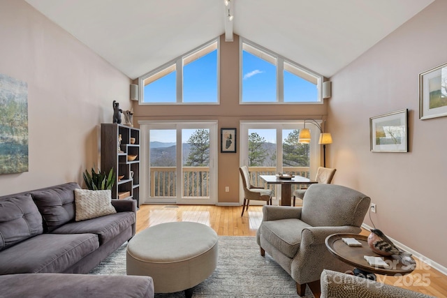 living room featuring beam ceiling, high vaulted ceiling, and light hardwood / wood-style flooring