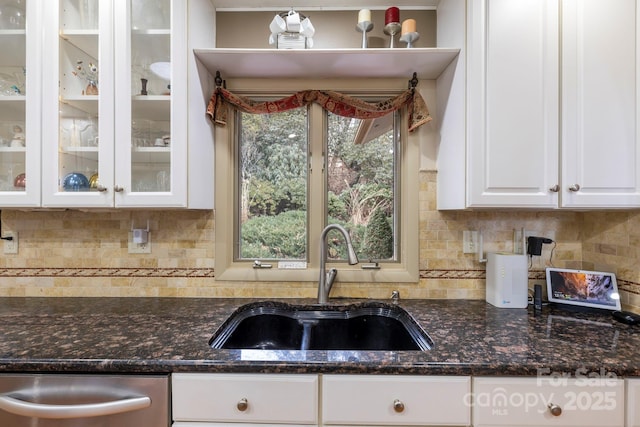 kitchen with dishwasher, white cabinetry, sink, and dark stone counters