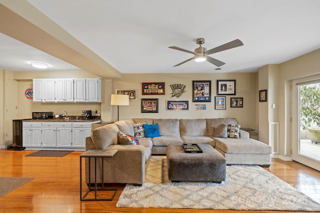 living room with sink, light hardwood / wood-style floors, and ceiling fan