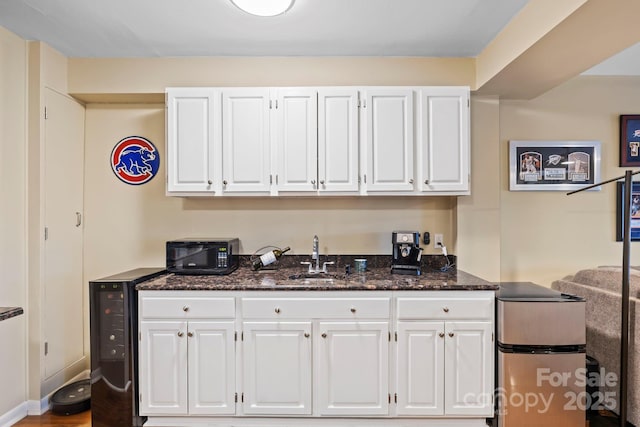 kitchen featuring dark stone counters, sink, and white cabinets