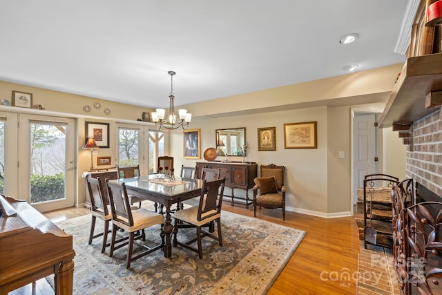 dining space with a fireplace, light hardwood / wood-style flooring, and a chandelier