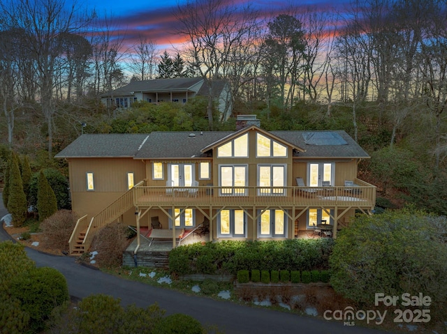 back house at dusk featuring a deck