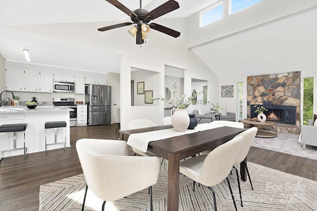 10912 Treebark Dr, Charlotte, NC 28226 - dining area featuring dark wood finished floors, high vaulted ceiling, plenty of natural light, a ceiling fan, and a stone fireplace