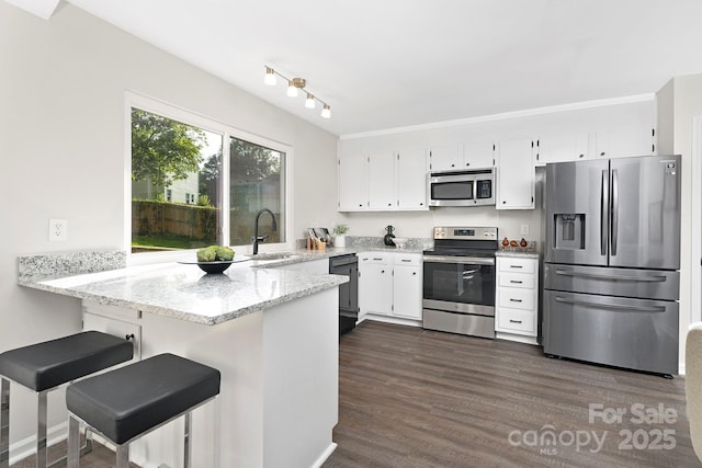 10912 Treebark Dr, Charlotte, NC 28226 - kitchen featuring appliances with stainless steel finishes, a sink, a peninsula, white cabinetry, and light stone counters