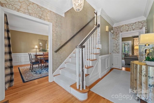 stairway with hardwood / wood-style flooring, ornamental molding, and an inviting chandelier