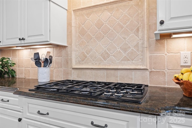 kitchen featuring backsplash, white cabinetry, dark stone counters, and black gas stovetop