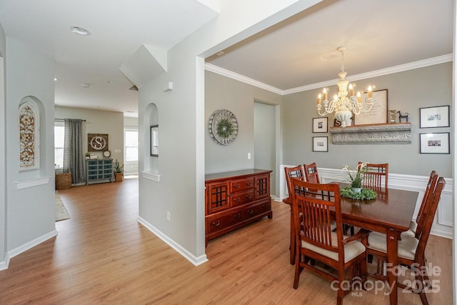 dining area with crown molding, a chandelier, and light hardwood / wood-style flooring