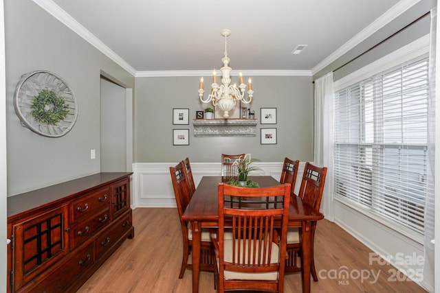 dining space with an inviting chandelier, ornamental molding, and light hardwood / wood-style floors