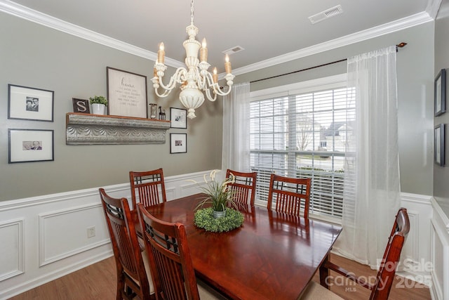 dining area with a notable chandelier, hardwood / wood-style flooring, and ornamental molding